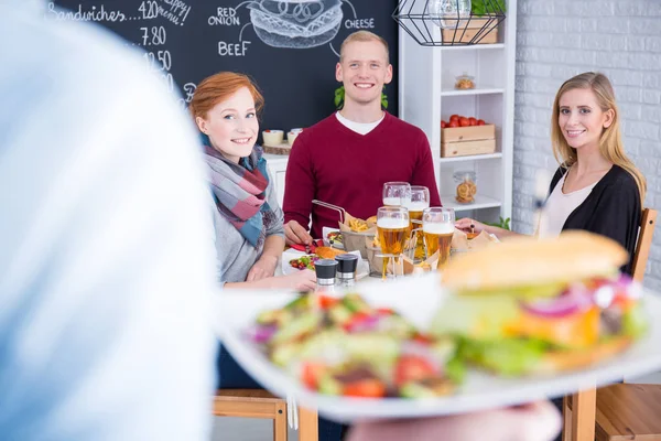 Person serving cheeseburger with salad — Stock Photo, Image