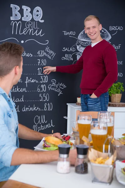 Muž, který stojí vedle burger menu — Stock fotografie