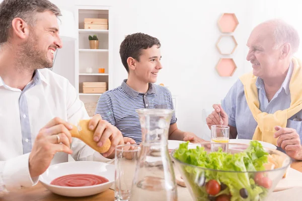 Boy eating dinner with grandfather — Stock Photo, Image