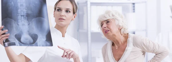 Doctor watching X-rays with patient — Stock Photo, Image