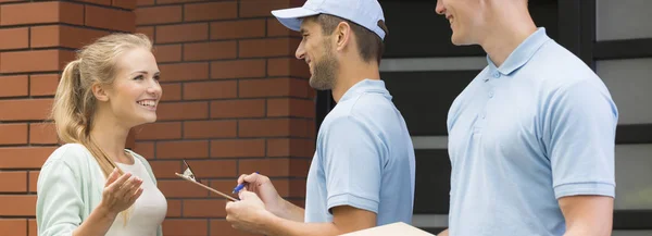 Jonge vrouw praten met koeriers in uniformen — Stockfoto