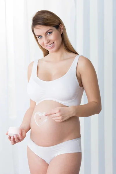 Frau malt ein Herz auf Bauch — Stockfoto