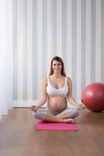 Улыбающаяся беременная женщина практикующая йогу — стоковое фото
