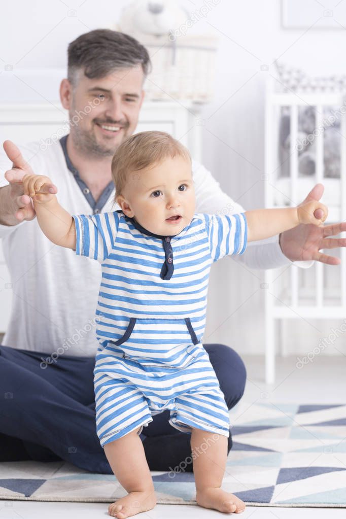 Baby making first steps with father
