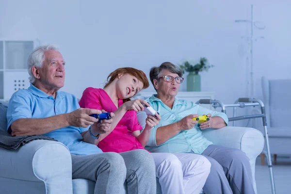 Cuidador jogar jogos de vídeo com casal de idosos — Fotografia de Stock