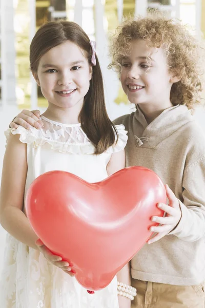 Pareja pequeña sosteniendo corazón rojo — Foto de Stock