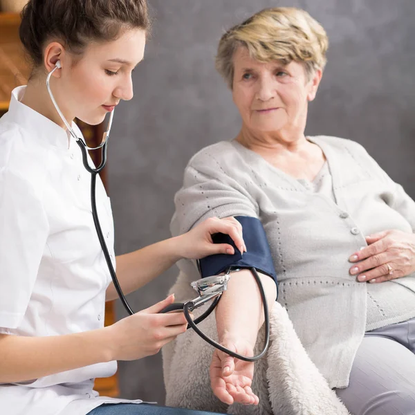 Enfermera tomando la presión arterial de la mujer de edad avanzada —  Fotos de Stock