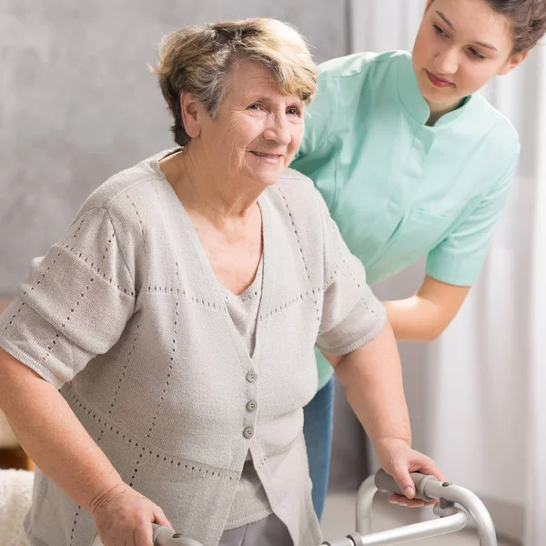 Senior vrouw met walker en verzorger — Stockfoto