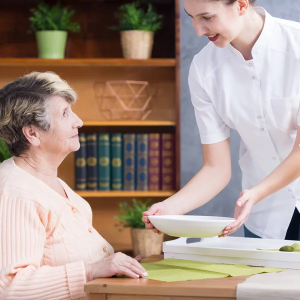 Verzorger soep serveren aan senior dame — Stockfoto