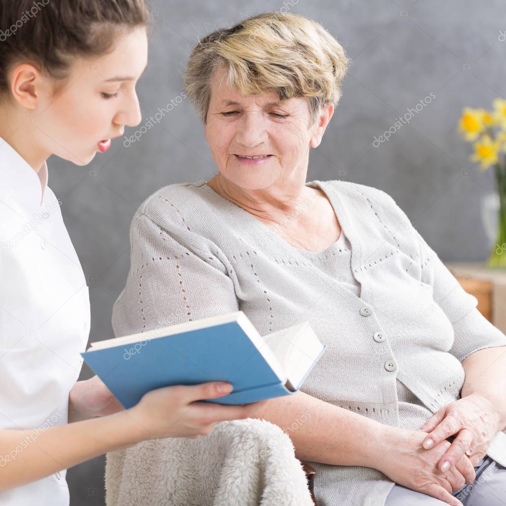 Caregiver reading to elderly woman