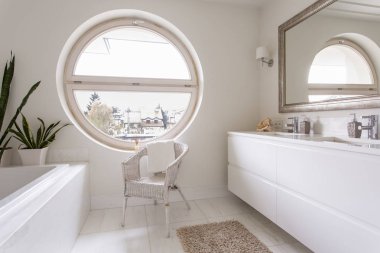 Büyük yuvarlak pencere ile beyaz banyo