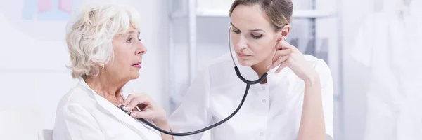 Arzt hört durch ein Stethoskop zu — Stockfoto