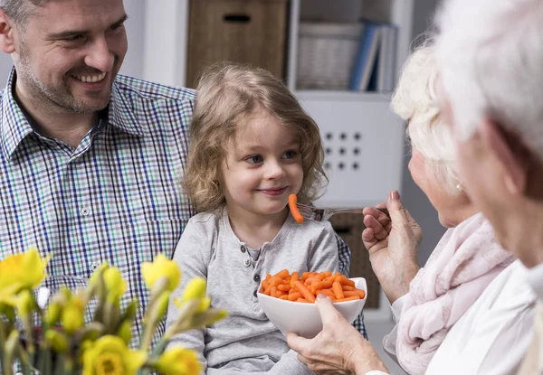 Grootmoeder voeden met gezonde wortelen kleinkind — Stockfoto