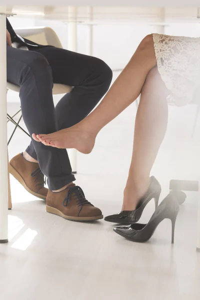 Donna seducente toccando l'uomo con la gamba — Foto Stock