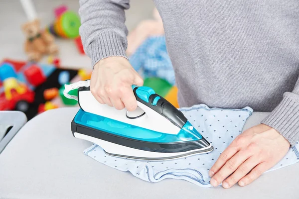 Papá joven planchando ropa de bebé — Foto de Stock
