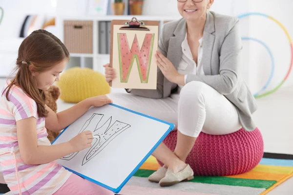 Therapist and girl drawing letter — Stock Photo, Image