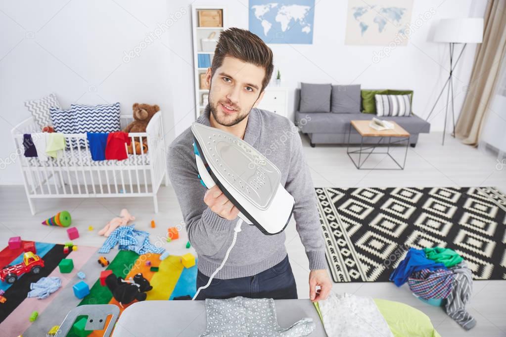 Modern father ironing baby clothes