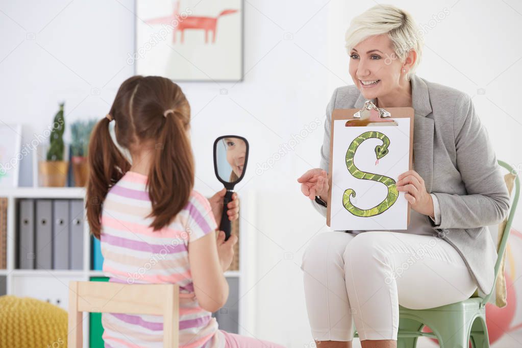 Speech therapist and girl holding mirror