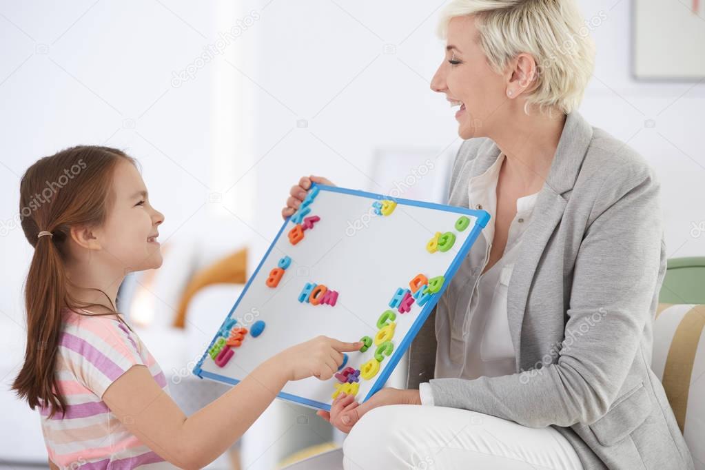 Girl learning alphabet with tutor