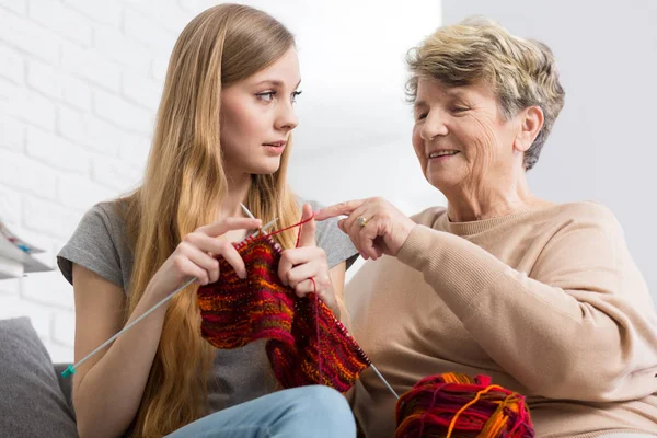 Grandma teaching granddaughter how to knit