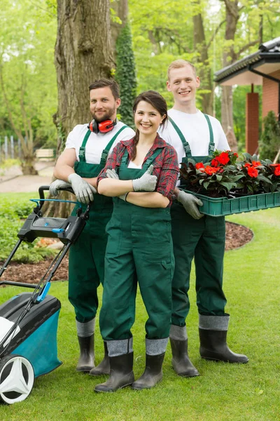 Happy gardeners with plants and lawn mower — Stock Photo, Image