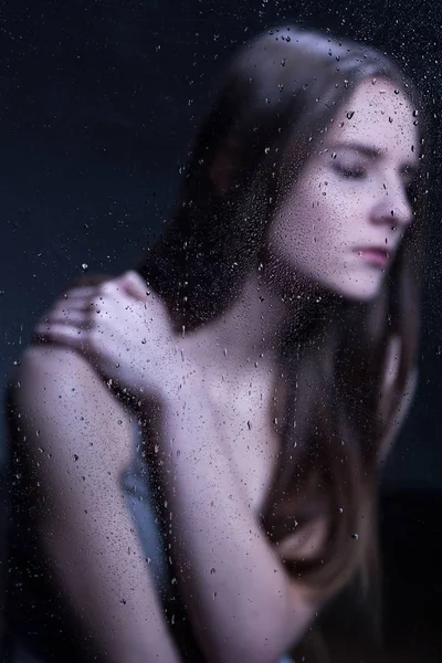 Молодая, грустная женщина за стеклом — стоковое фото