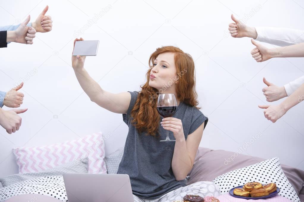 Woman taking selfie on bed