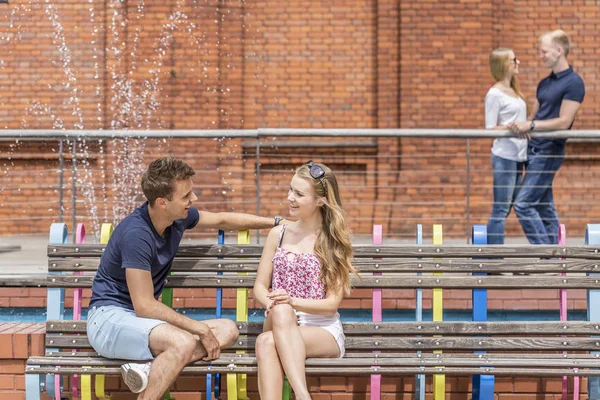 Jovem casal flertando em um banco — Fotografia de Stock