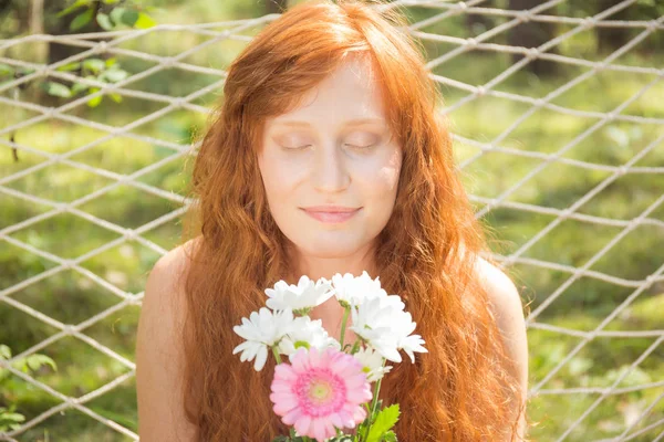Mujer pelirroja natural oliendo flores —  Fotos de Stock