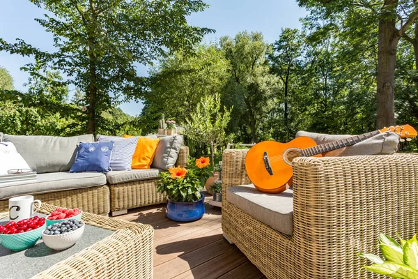 Summer patio with rattan furniture and guitar