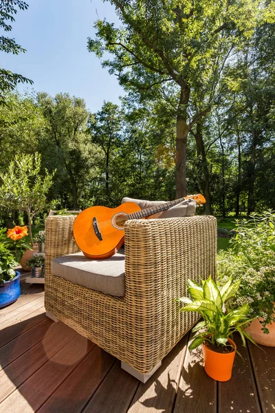 Gitaar op een tuin sofa tijdens zonnige dag — Stockfoto