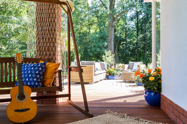 A guitar standing beside a garden swing
