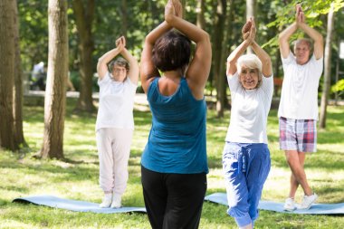 Bir yoga sınıfı açık havada olan yaşlılar gülümseyen