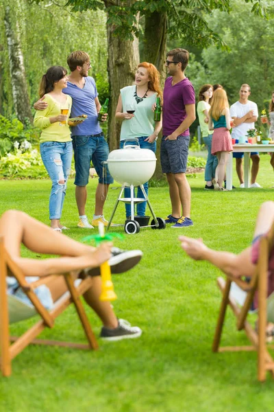 Friends standing beside barbecue grill — Stock Photo, Image