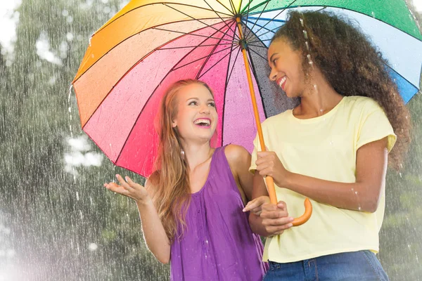 Freunde gehen mit buntem Regenschirm — Stockfoto