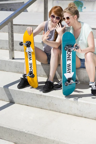 Улыбающиеся девушки сидят со скейтбордами — стоковое фото