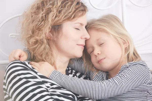 Kleines Mädchen umarmt ihre Mutter, während sie schläft — Stockfoto