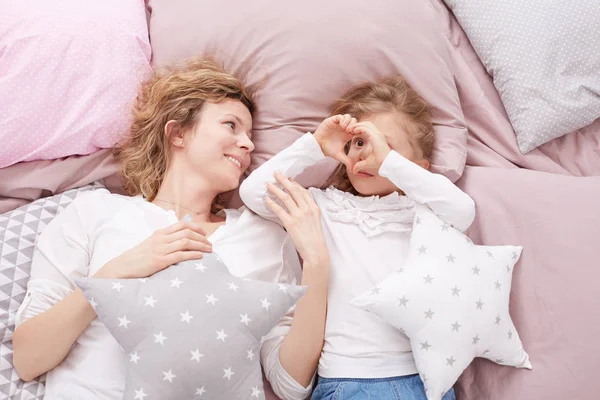 Moeder en dochter opleggen van een bed — Stockfoto