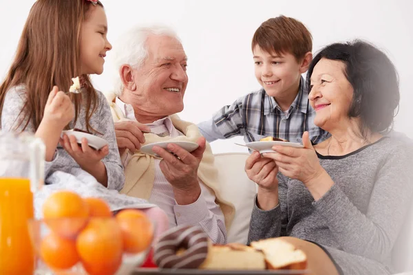 Abuelos y nietos comiendo un pastel — Foto de Stock