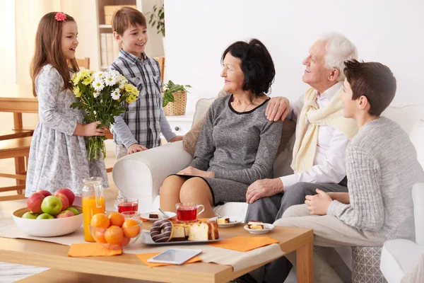 Children giving flowers to grandparents — Stock Photo, Image