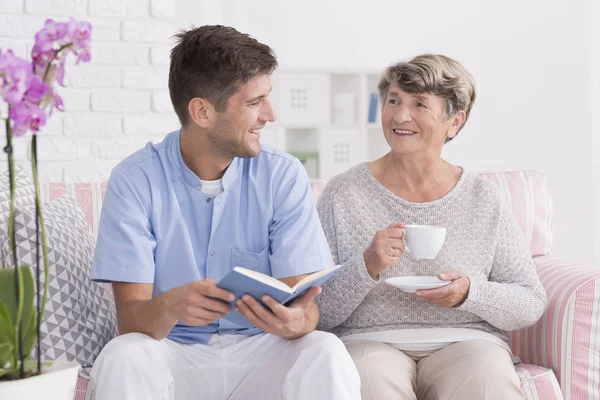 Professionelle Pflegekraft liest Senioren vor — Stockfoto