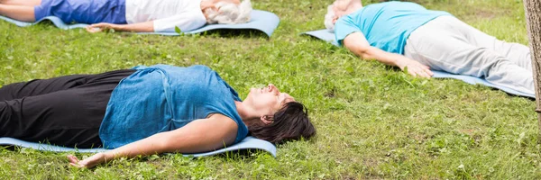 Idosos deitados na grama no parque — Fotografia de Stock