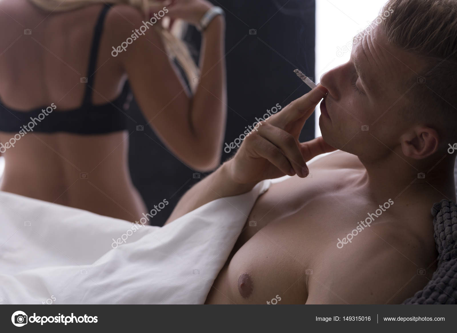 Young man smoking cigarette after sex Stock Photo by ©photographee.eu 149315016