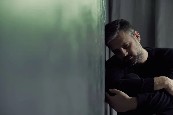 Hombre sentado al lado de una pared — Foto de Stock