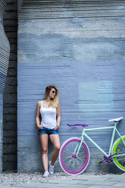 Подходит девушка, одетая рядом с велосипедом — стоковое фото