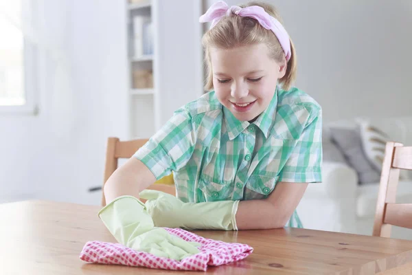 Menina limpando uma mesa com pano de limpeza — Fotografia de Stock