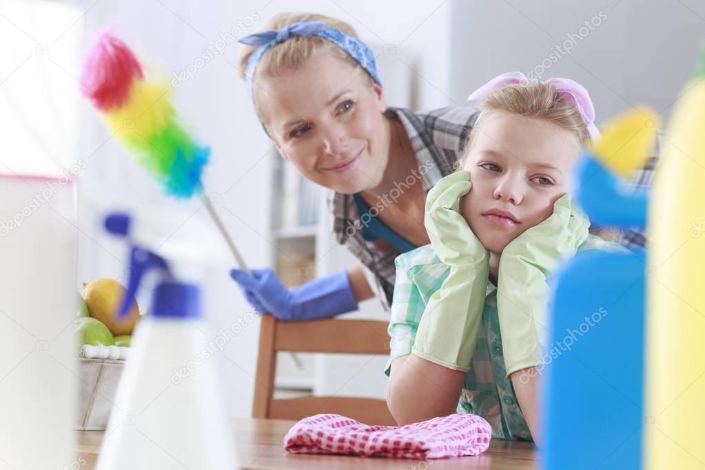 Sad girl and her mom cleaning