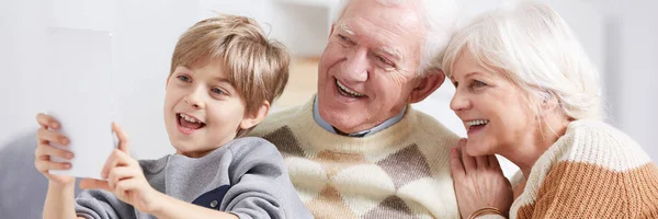 Хлопчик показує планшет бабусям і дідусям — стокове фото