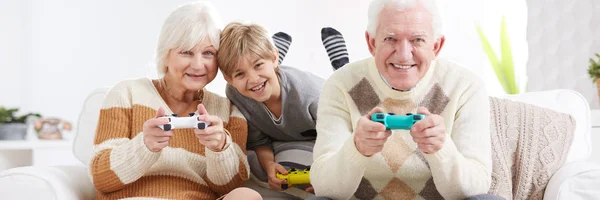 Garçon jouer à des jeux vidéo avec les grands-parents — Photo