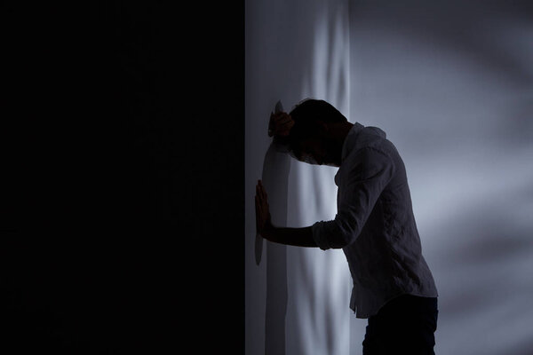 Man leaning head against wall